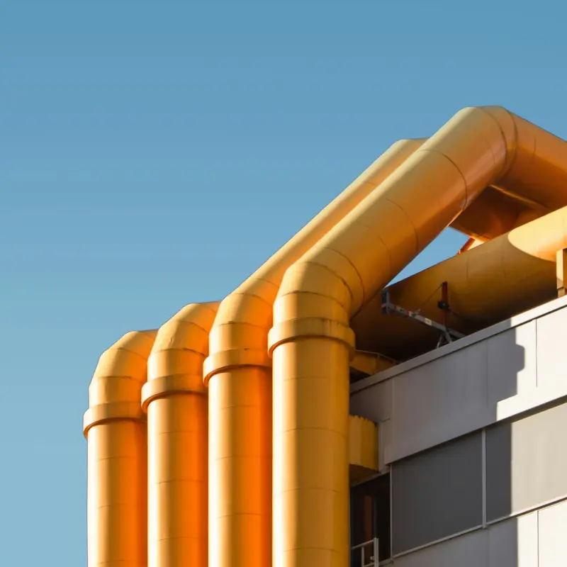 Large orange industrial pipes on a building against a blue sky